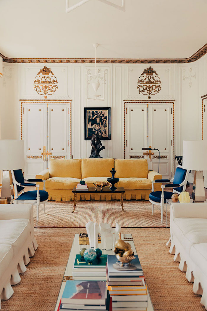 appartement design decoration canapé jaune tapis beige chaises blanc et bleu canapés blancs murs blancs et déco murale à accents dorés