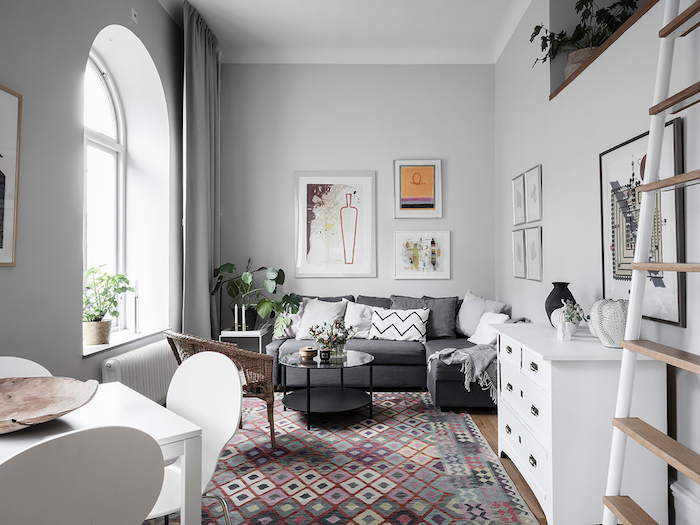 deco appartement parisien style scandinave avec canapé gris mobilier blanc tapis coloré géométrique rideaux gris plantes vertes