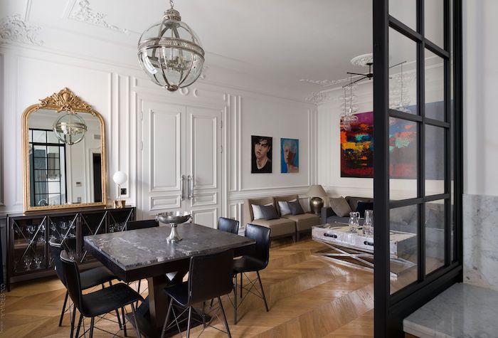 deco haussmannien avec table et chaises noires canapé gris et table coffret inox parquet bois clair murs blancs décorés de peinture art contemporain