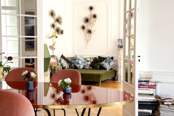 deco murale de fleurs canapé vert olive table et chaises salle à manger rouges parquet chevron clair piles de livres