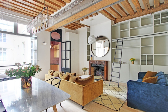 deco petit appartement studio abec canapé jaune et canapé bleu table marbre et bois meuble salon gris clair miroir rond au dessus de cheminée