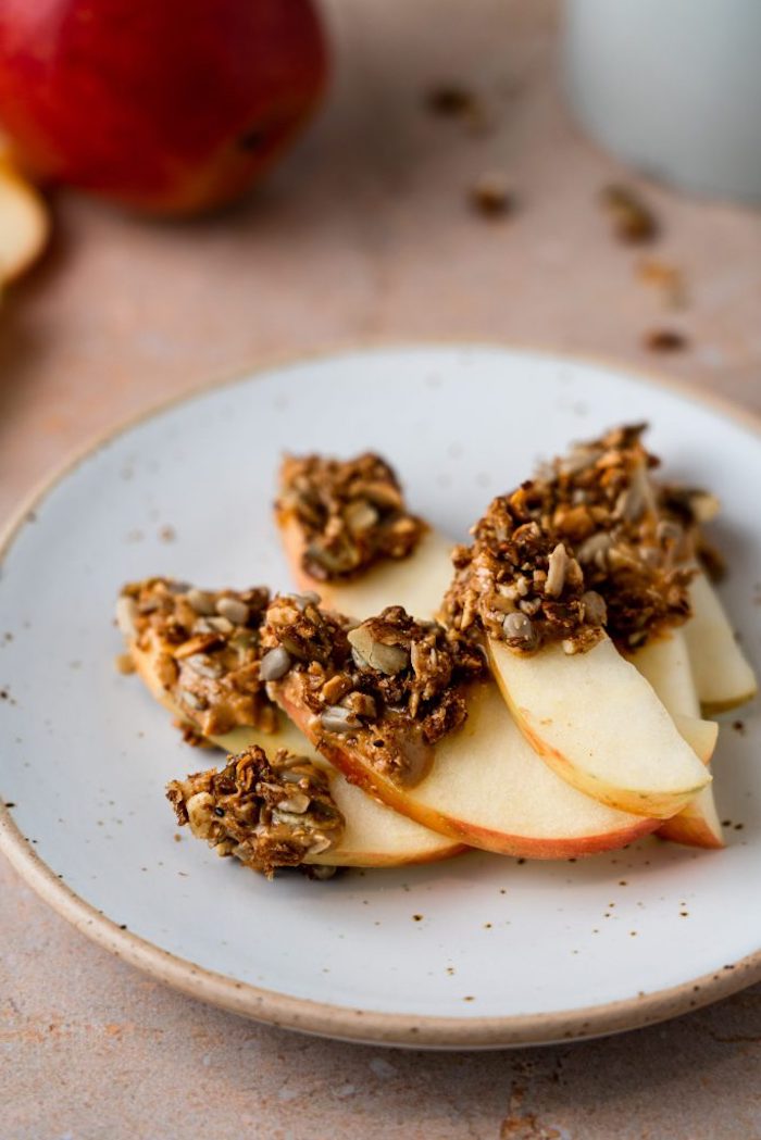 idée de tranches de pomme avec granola au beurre de cacahuete constitutée de graines flocons noix de coco et autres