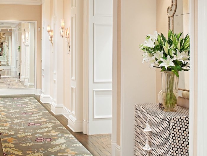 idée peinture couloir beige saumon avec des portes blanches parquet bois ancien tapis gris fleuri meuble couloir original