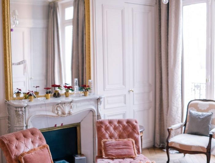 lustre à pampilles colorées fauteuils saumon capitonnés tapis oriental coloré table basse design fausse cheminée et miroir encadrement or décoration appartement moderne