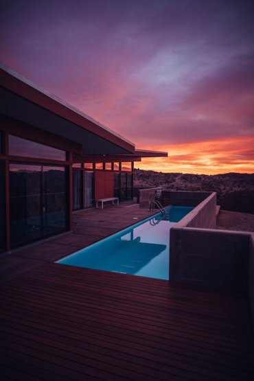 maison de luxe à toiture plate en bois et verre avec terrasse de bois et petite piscine