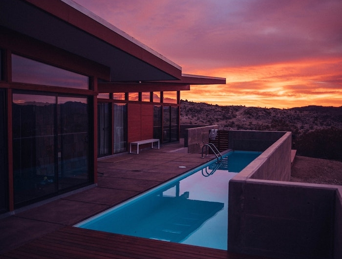 maison de luxe à toiture plate en bois et verre avec terrasse de bois et petite piscine