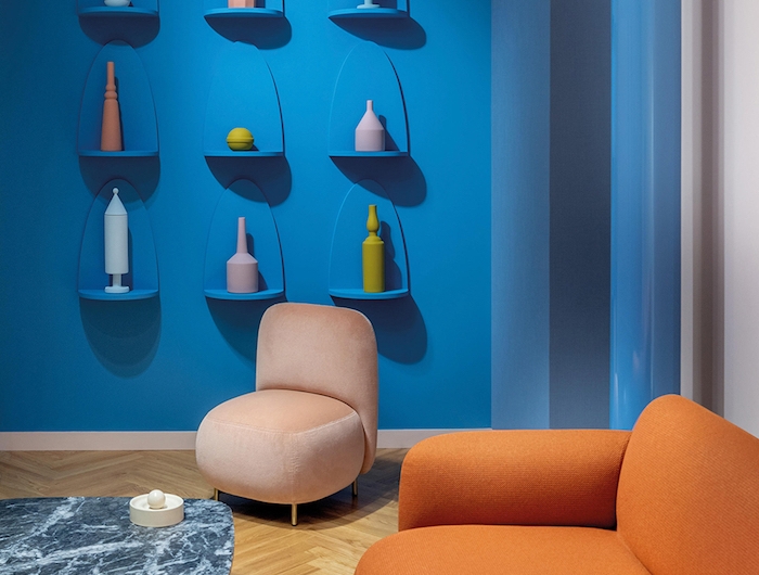 mobilier aux contours arrondis canapé orange et fauteuil beige table marbre gris mur bleu avec des vases arrondis meuble année 70