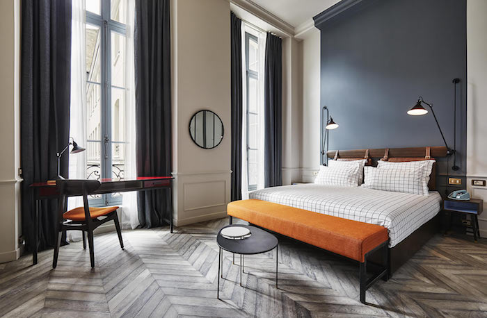 pan de mur gris lit bois et linge de lit à carreaux bout de lit orange coin bureau vintage rideaux grises idee interieur appartement industriel