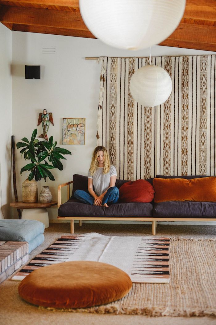plafond de bois canapé boid avec coussin de dos et d assise gris anthracite et des coussins coloré pouf marron clair tapis beige plabte verte rideau voilage mural