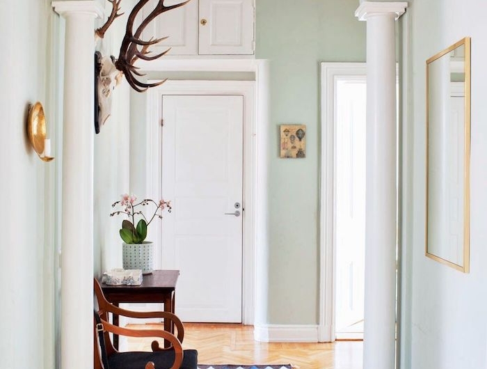 quelle couleur pour un couloir d entrée murs vert pastel colonnes blanches parquet clair tapis geometrique chaise bois et noir deco murale originale