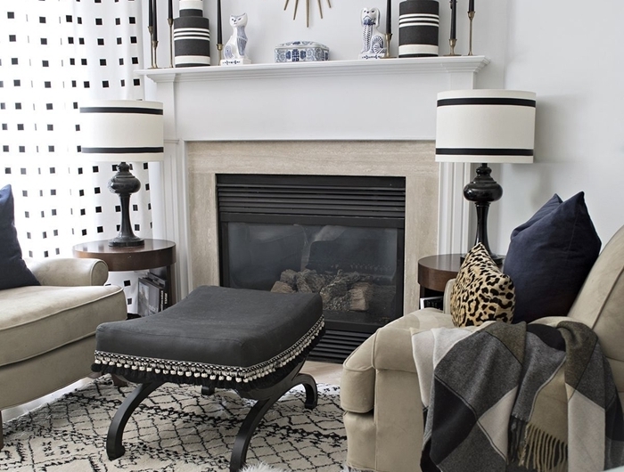 salon noir et blanc avec accents en or miroir soleil cheminée pierre vase rayures blanc et noir fauteuil beige tapis moelleux blanc