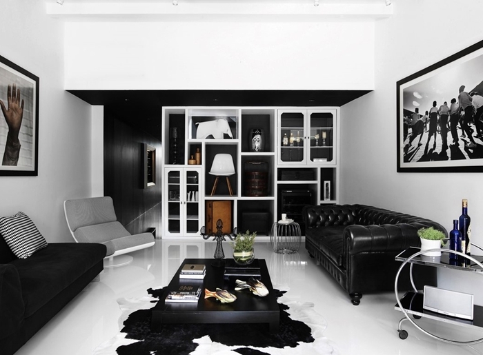 table basse noire tapis imitation peau animale canapé noir velours mat peinture noir et blanc art mural bibliothèque blanche