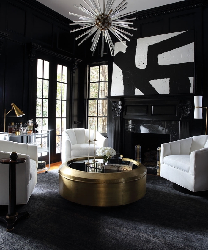 table basse ronde en or et verre tableau noir et blanc abstrait salon noir et blanc avec cheminée fauteuiles blancs parquet bois