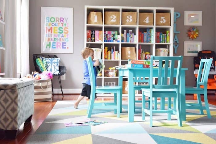 table et chaises pret de l etagere avec les jouets endant tapis geometrique belles couleursidée déco salle de jeux meuble de rangement jouet simplicité