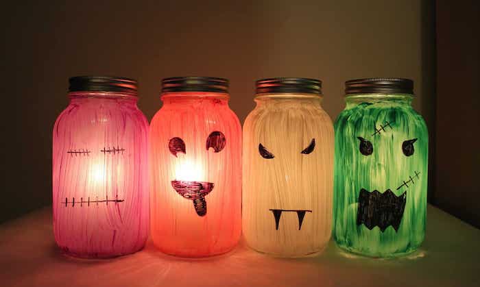 bocaux en verre repeints de peinture avec de smotifs monstre citrouille dessinés et bougies pour creer une deco halloween a faire soi meme terrifiante