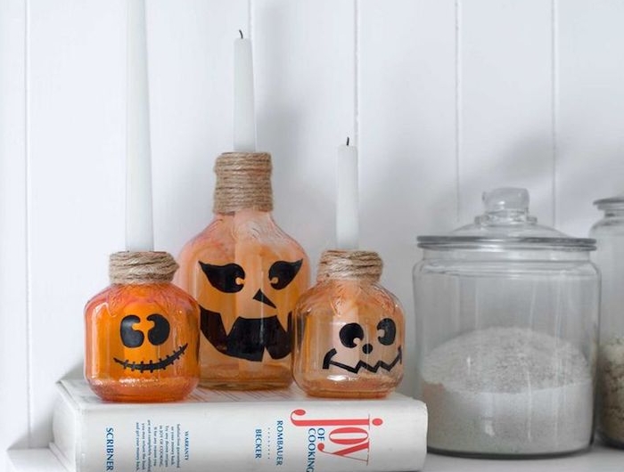 bouteilles d everre rpeint de peinture orange semi transparente avec motif citrouille jack o lantern et ficelle de chanvre autour du col deco halloween facile a faire