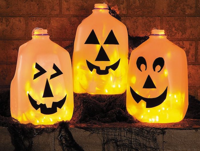 bouteilles de jus lait recyclées avec des guirlandes lumineuses a l interieur et motif jack o lantern d;ecoration halloween à fabriquer