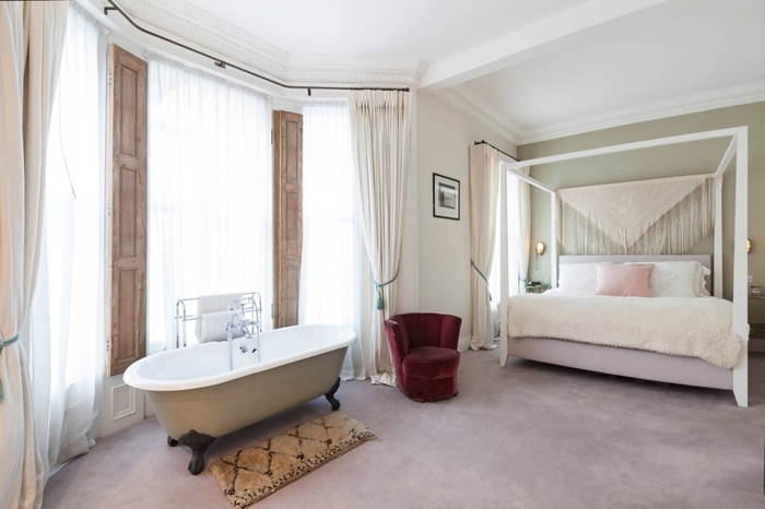 chambre avec salle de bain rideaux blancs tête de lit macramé cadre de lit blanc coussin rose pastel fauteuil velours bordeaux