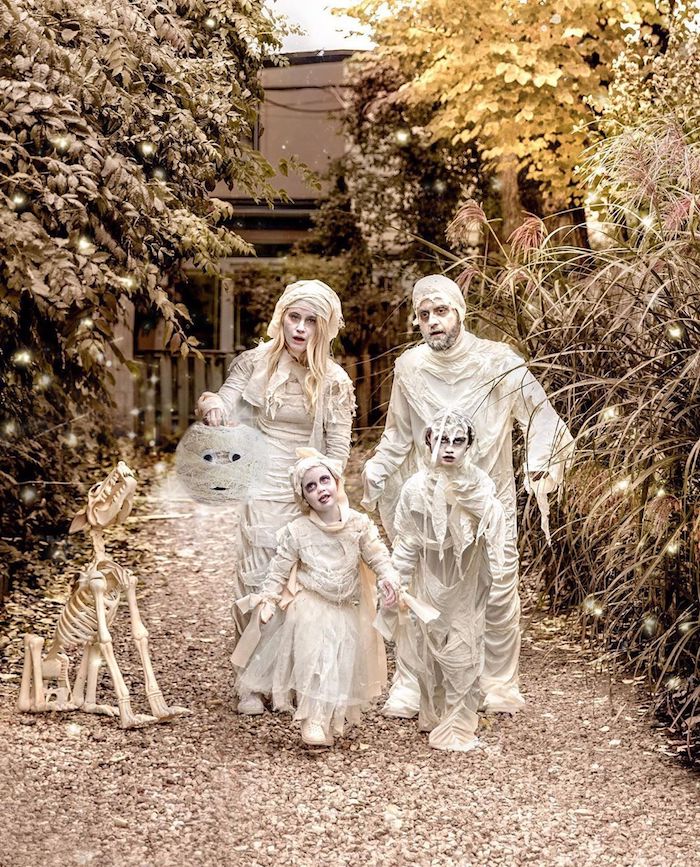 deguisement halloween fait maison momies et maquillage blanc utilisation de papier diy une famille devant grande porte dqns la foret