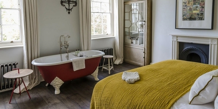 déco appartement parisien salle de bain dans chambre revêtement parquet bois foncé table café bois et métal couverture de lit jaune moutarde