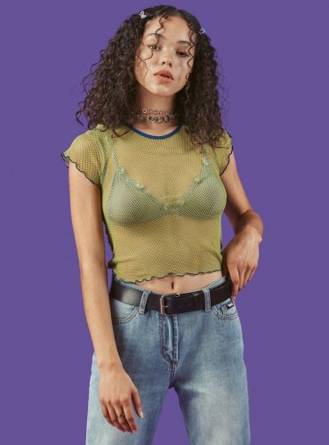 jeune femme look année 2000 en top résille et jean avec un colier type choker
