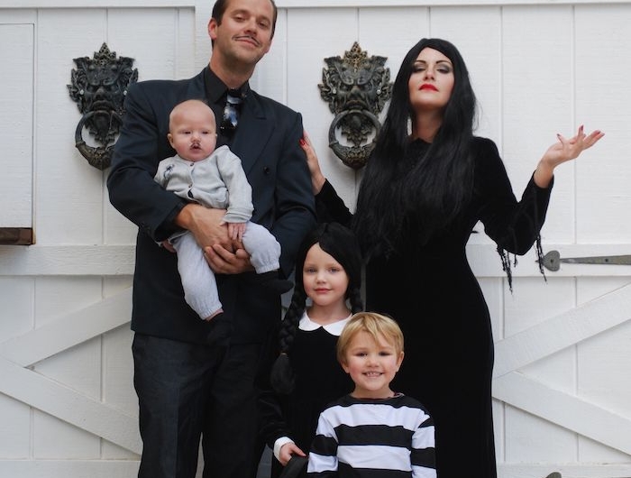 la famille addams idee costume halloween devant une porte blanche costumes noirs des longues tresses