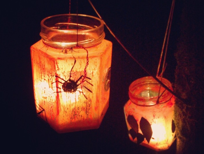 lanterne halloween dans pot en verre bougie halloween et motifs feuilles araignée et peinture orange pour decorer l exterieur du pot