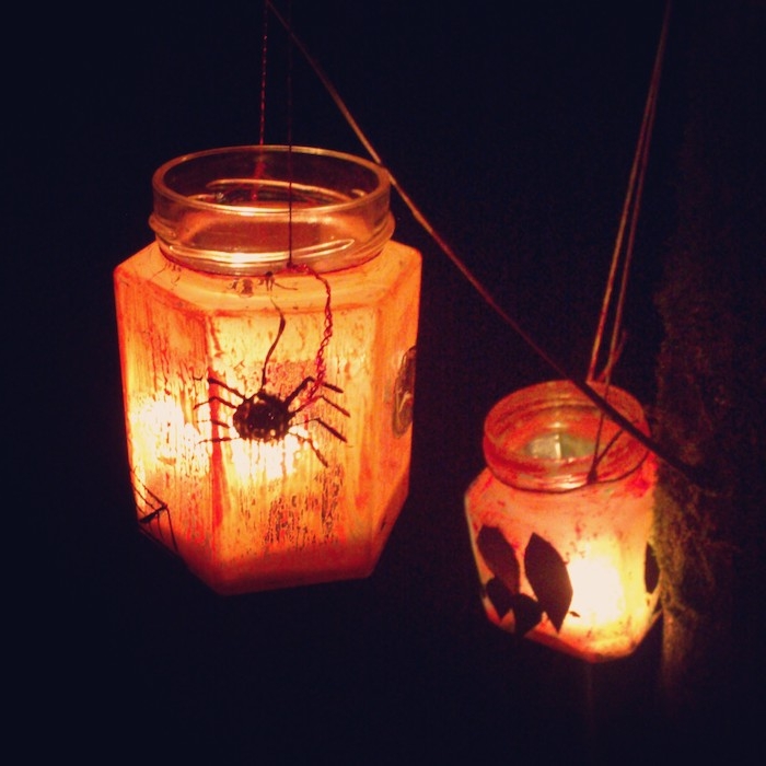 lanterne halloween dans pot en verre bougie halloween et motifs feuilles araignée et peinture orange pour decorer l exterieur du pot