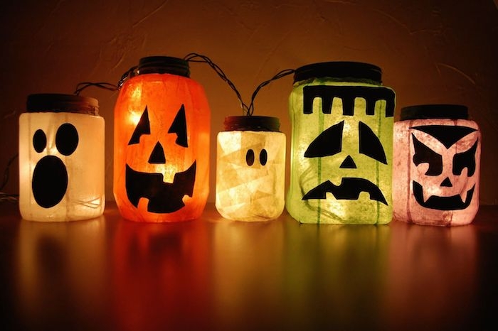 lanterne halloween décoré de petits bouts de papier de soie et des stickers noirs motif monstre jack o lantern et guirlande lumineuse