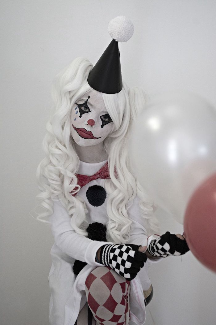 maquillage halloween de clown pour des enfants costume en noir et blanc et perruque une fille qui tient des bqllons
