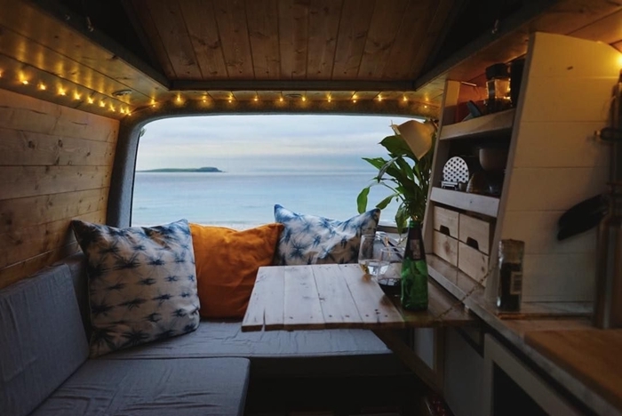 mini van aménagé camping car déco bohème meubles convertibles table repas canapé lit coussins décoratifs guirlande led