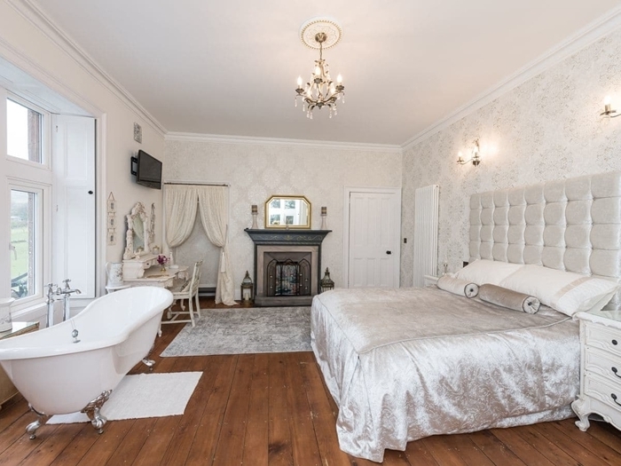 parquet bois salle d eau dans chambre couverture de lit lustre rideaux blancs cheminée décorative miroir or papier peint
