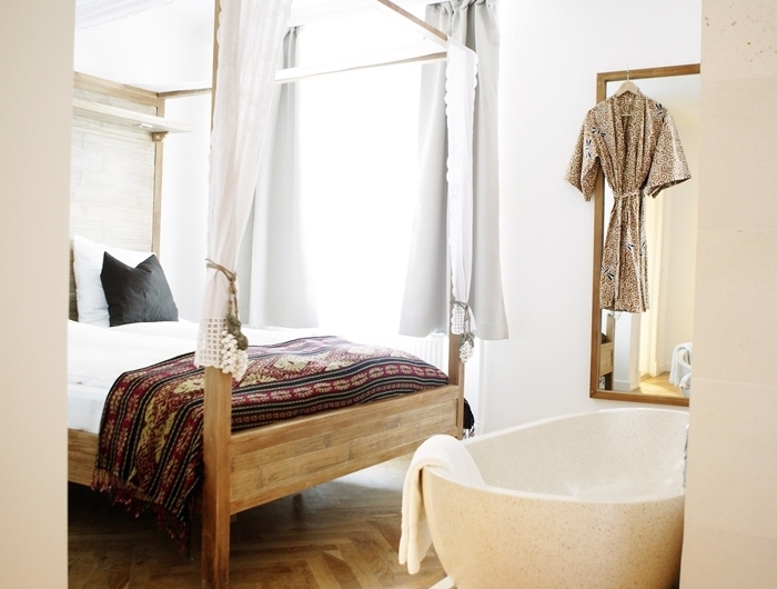 revêtement de sol parquet bois clair baignoire dans chambre autoportante cadre de lit bois baldaquin couverture de lit motifs ethniques
