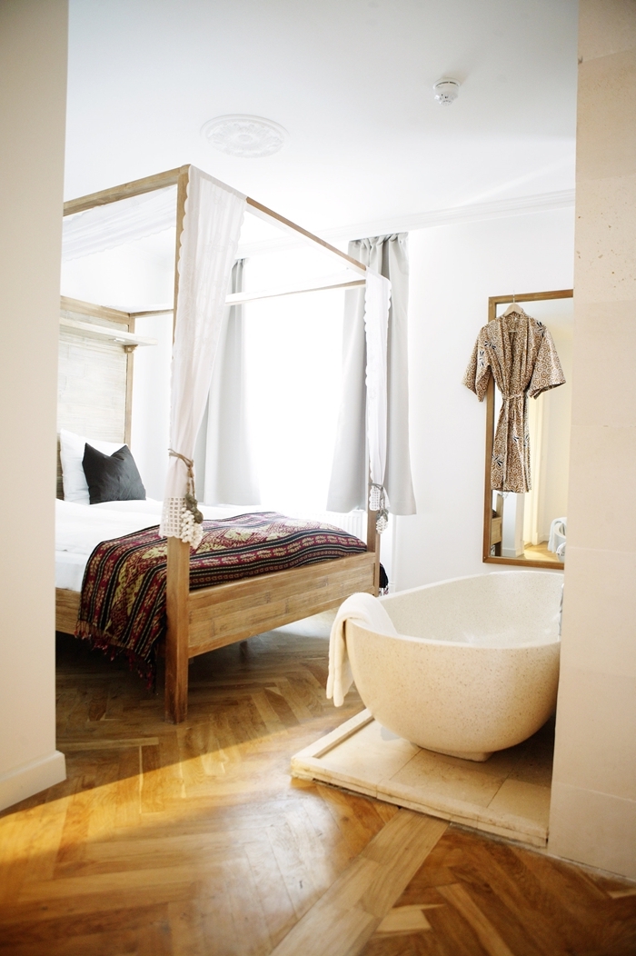 revêtement de sol parquet bois clair baignoire dans chambre autoportante cadre de lit bois baldaquin couverture de lit motifs ethniques
