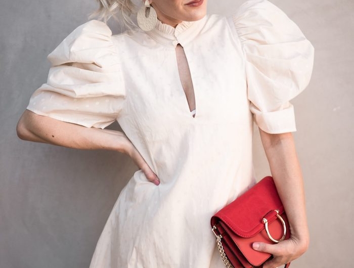 robe manche ballon en blanc portee avec un sac a main rouge boucles d oreilles et lunettes