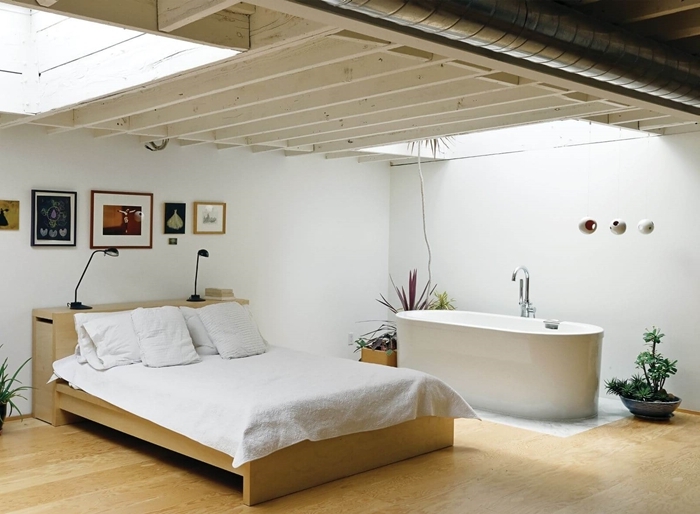 salle de bain ouverte sur chambre revêtement de sol parquet bois lit bois plantes vertes intérieur mur cadres bois
