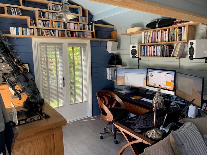studio de jardin en style rondin des livres sur les etageres des ordinateurs sur le bureau er murs bleues