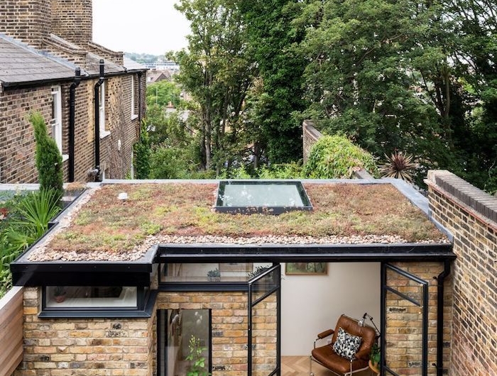 studio de jardin habitable en pierre avec un toit plat et cadres noirs en style moderne