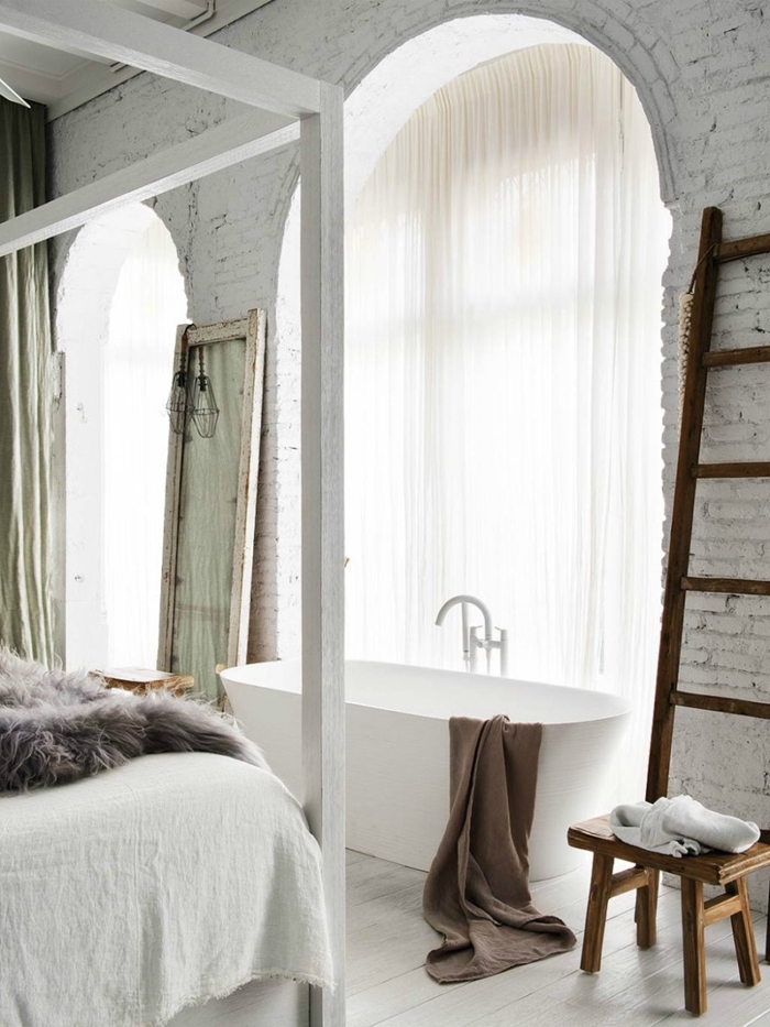 échelle décorative bois tabouret baignoire dans chambre décoration mur briques blanches cadre de lit bois blanc plaid fausse fourrure grise