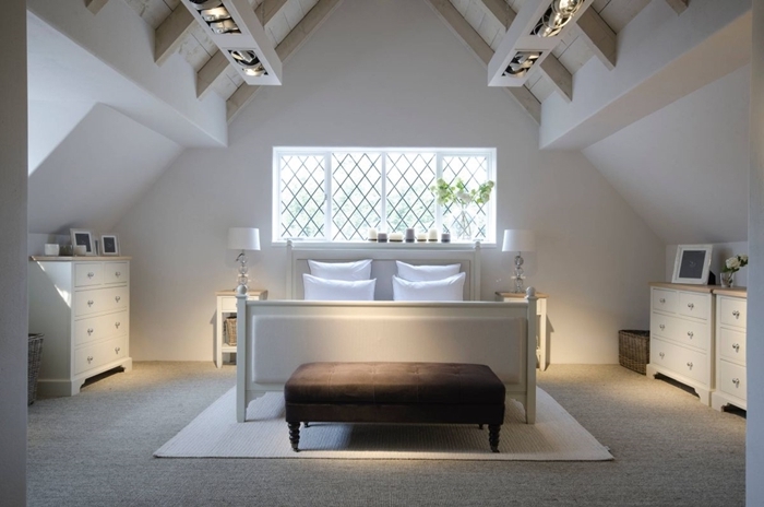 aménagement sous comble chambre adultes murs blancs plafond poutres bois blanc cadre de lit banquette velours