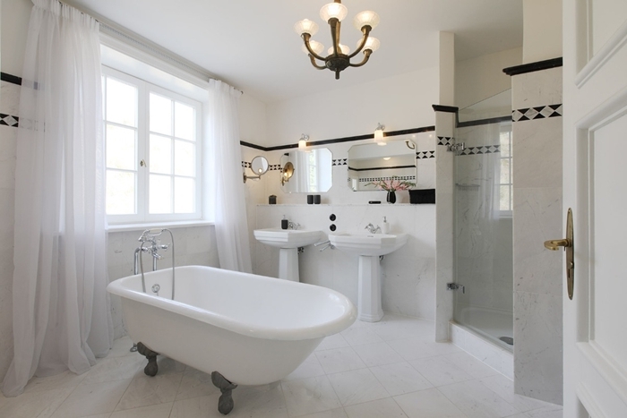 baignoire sur pied salle de bain style ancien double lavabo évier sur piédestal miroir rideaux longs blancs carrelage blanc