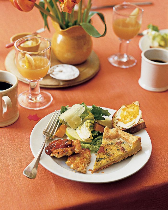 brunch healthy avec0des oeufs et des tartines beurres servi avec jus et de cafe sur une nappe orange
