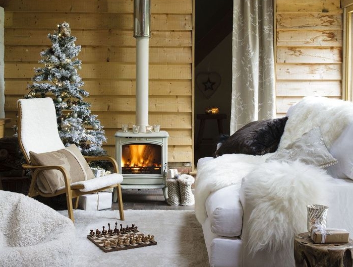 canapé blanc tapis et fauteuil blancs chaise bois cheminée rustique mur de bois et sapin de noel décoré deco chic rustique