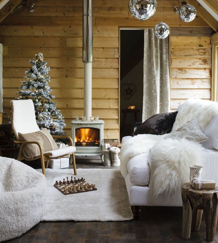 canapé blanc tapis et fauteuil blancs chaise bois cheminée rustique mur de bois et sapin de noel décoré deco chic rustique