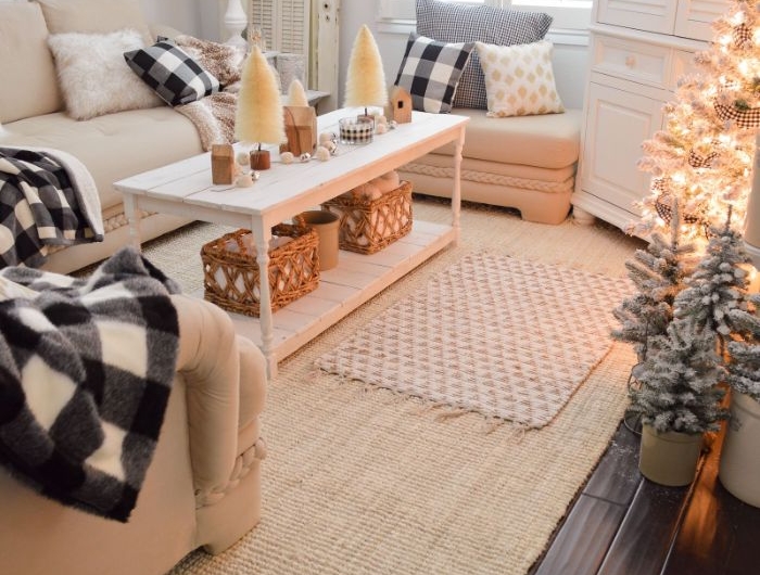 canapés blanc cassé tapis à franges table basse blanche decoration de sapins de tailles variées coussins decoratifs