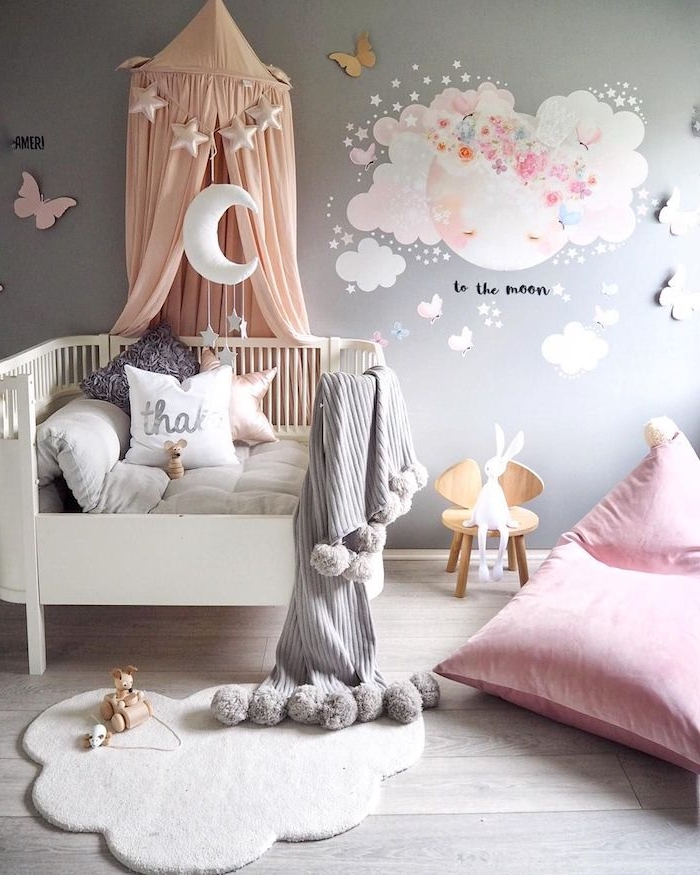chambre bébé fille déco avec lit blanc à barreaux tapis doux blanc coussin d assise rose mur gris clar sur parquet bois clair coussins décoratifs