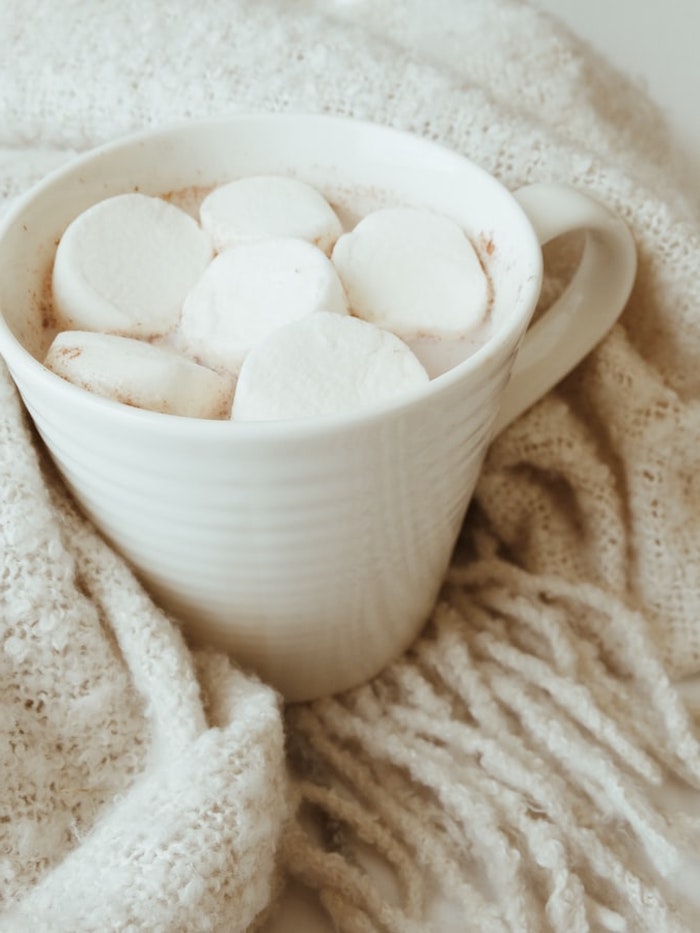 chocolat chaud blanc aux guimauves dans tasse blanche et couverture douillette idée boisson noel