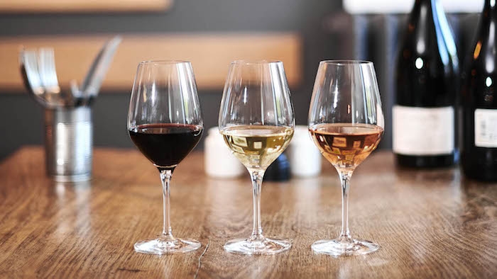 coment deguster et servir du vin trois verres a tige avec vin blanc rouge et rose sur une table en bois