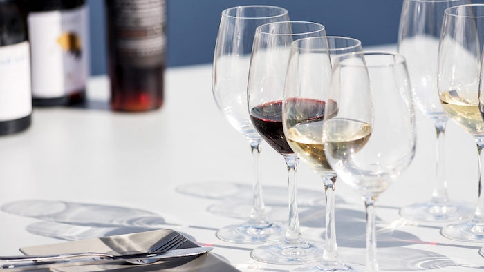 comment places les verres sur une table verres de vin rouge et blanc a cote de couverts et bouteilles de vin