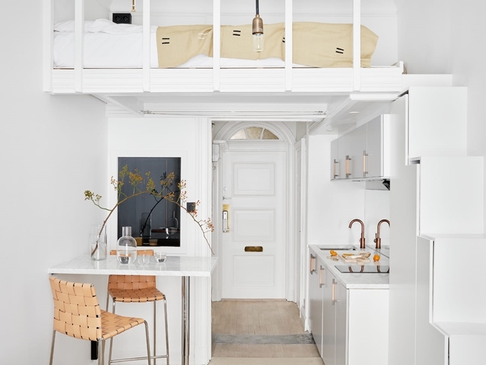 deco petit appartement en blanc et bois carrelage pierre robinet rose gold armoires blanches îlot bar mezzanine lit